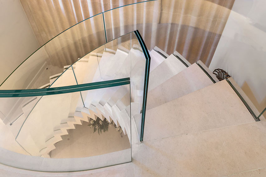 Идея дизайна: лестница на больцах в современном стиле с ступенями из известняка, подступенками из известняка и стеклянными перилами