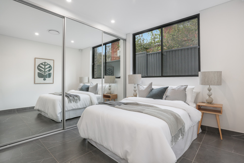 Bedroom - large modern guest ceramic tile, gray floor, shiplap ceiling and brick wall bedroom idea in Sydney with white walls and no fireplace