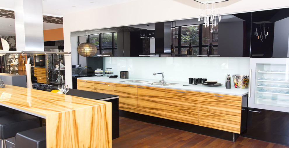 Photo of a large contemporary kitchen in Los Angeles with an undermount sink, flat-panel cabinets, black cabinets, white splashback, glass sheet splashback, stainless steel appliances, medium hardwood floors and with island.