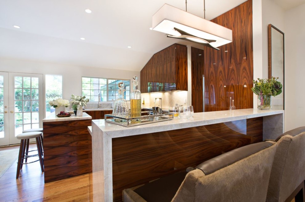 Inspiration for a mid-sized contemporary l-shaped open plan kitchen in Houston with flat-panel cabinets, medium wood cabinets, beige splashback, stone slab splashback, stainless steel appliances, medium hardwood floors, with island, an undermount sink, granite benchtops and beige floor.