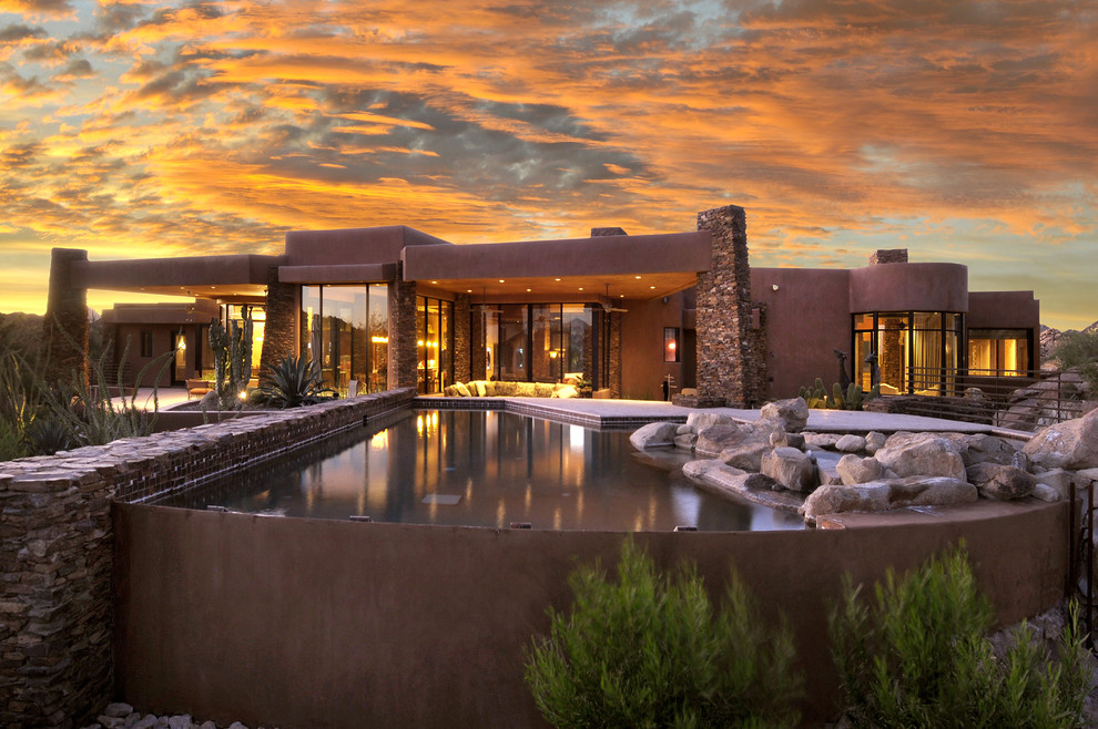 This is an example of a mid-sized backyard custom-shaped natural pool in Phoenix with concrete pavers.