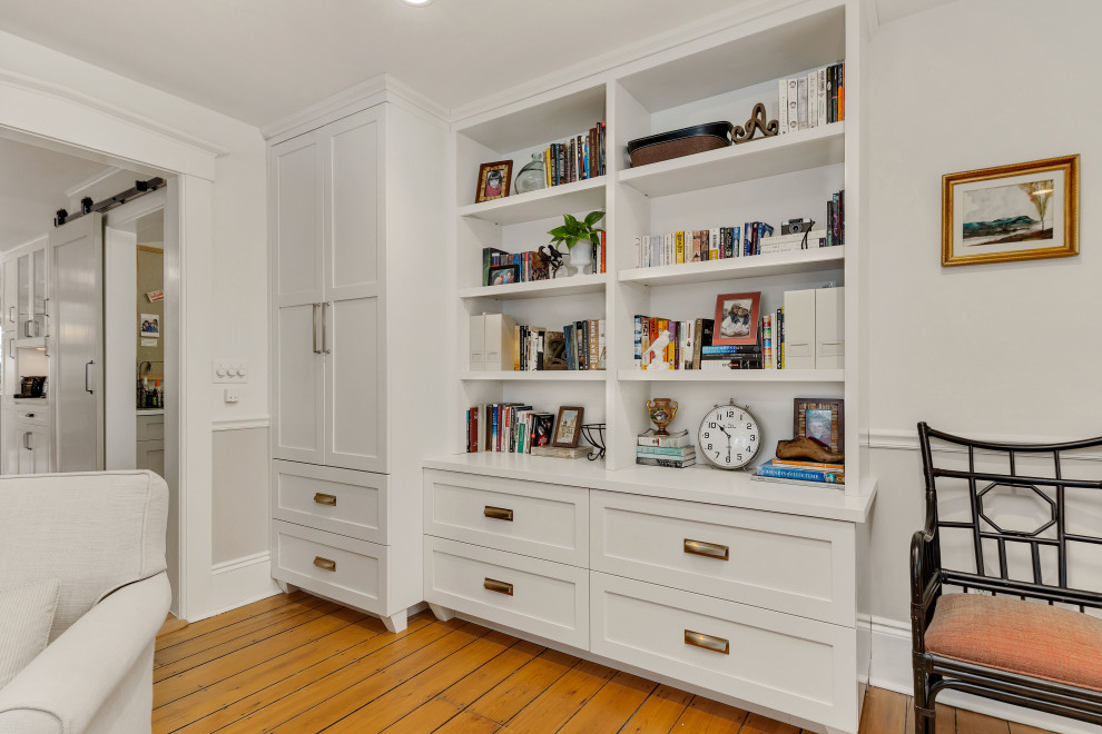 Exempel på ett mellanstort lantligt hemmabibliotek, med beige väggar, ljust trägolv, en standard öppen spis, en spiselkrans i sten, ett fristående skrivbord och brunt golv