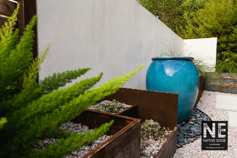 Photo of a small modern courtyard xeriscape in Austin with a water feature and gravel.
