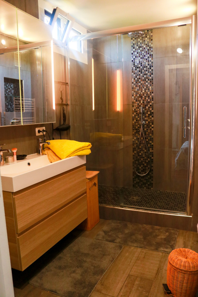 Mid-sized contemporary 3/4 bathroom in Paris with glass-front cabinets, light wood cabinets, a curbless shower, gray tile, ceramic tile, grey walls, wood-look tile, a trough sink, grey floor, a sliding shower screen, white benchtops, a double vanity and a floating vanity.