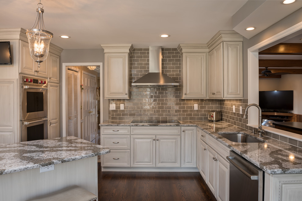 Design ideas for a large traditional l-shaped eat-in kitchen in Boston with raised-panel cabinets, white cabinets, quartzite benchtops, grey splashback, glass tile splashback, stainless steel appliances, dark hardwood floors, with island and brown floor.