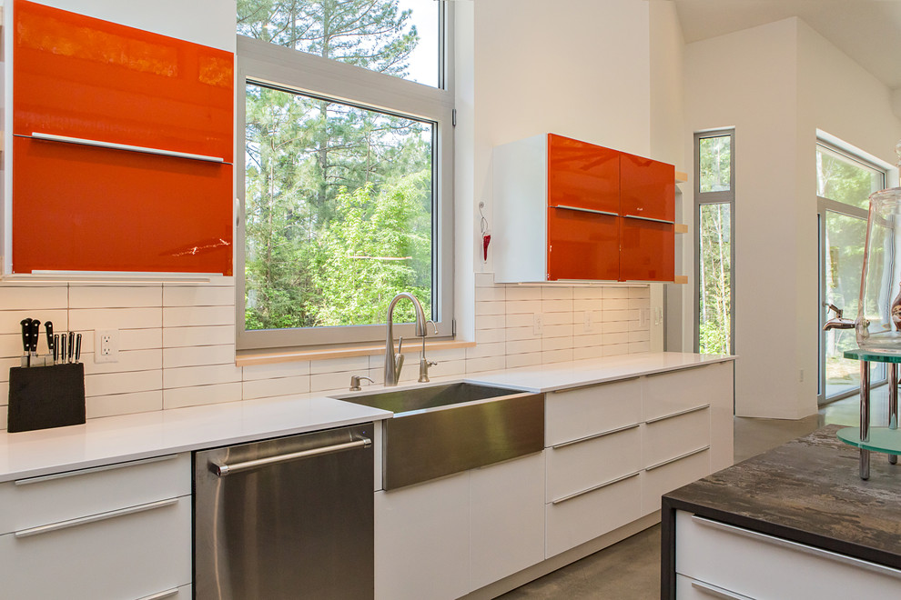 Photo of a mid-sized modern l-shaped open plan kitchen in Raleigh with a farmhouse sink, flat-panel cabinets, orange cabinets, quartz benchtops, white splashback, ceramic splashback, stainless steel appliances, concrete floors, with island, grey floor and multi-coloured benchtop.