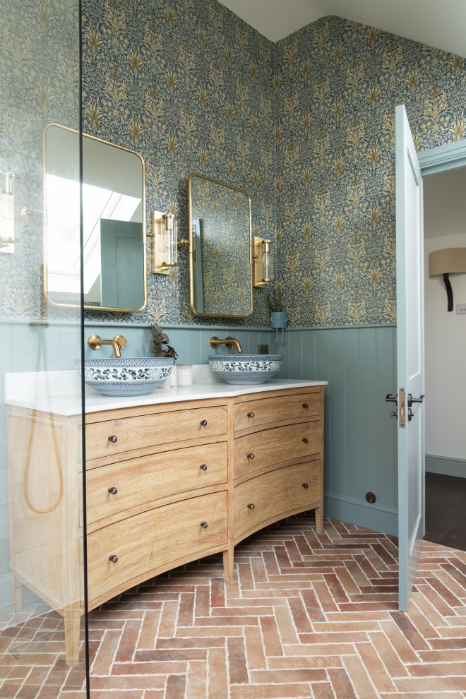 This is an example of a large eclectic ensuite wet room bathroom in Hertfordshire with flat-panel cabinets, light wood cabinets, a wall mounted toilet, blue tiles, ceramic tiles, blue walls, quartz worktops, an open shower, white worktops, double sinks, a freestanding vanity unit, a vaulted ceiling and wallpapered walls.