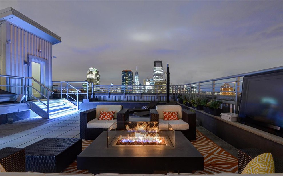 This is an example of a large contemporary rooftop full sun garden for summer in New York with a fire feature and concrete pavers.