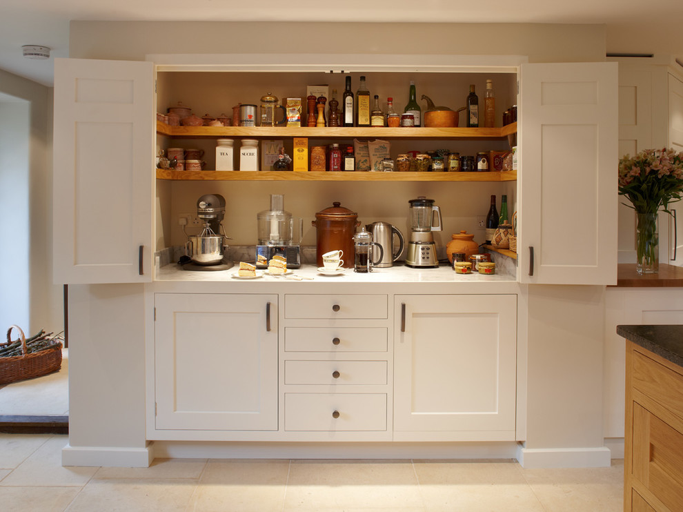 This is an example of a large traditional kitchen pantry in Surrey with shaker cabinets, white cabinets, marble benchtops and limestone floors.