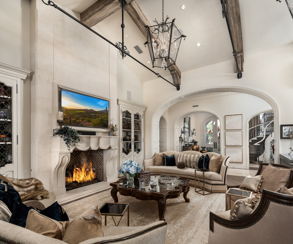 This is an example of an expansive mediterranean enclosed family room in Phoenix with a home bar, beige walls, medium hardwood floors, a standard fireplace, a stone fireplace surround, a wall-mounted tv and brown floor.