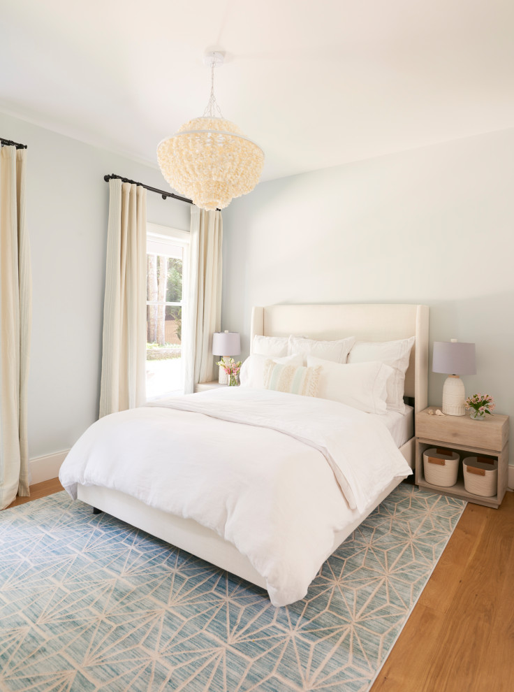 This is an example of a large beach style guest bedroom in New York with blue walls, medium hardwood floors, no fireplace and brown floor.