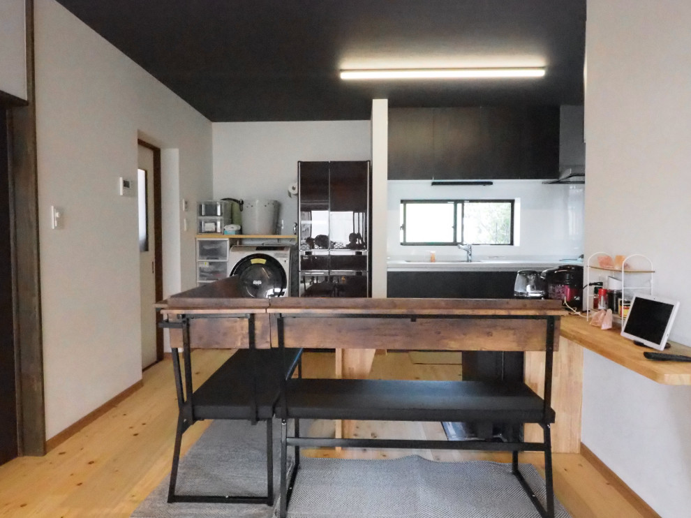 This is an example of a large modern grey and black single-wall open plan kitchen in Other with black cabinets, composite countertops, white splashback, light hardwood flooring, grey worktops and a wallpapered ceiling.