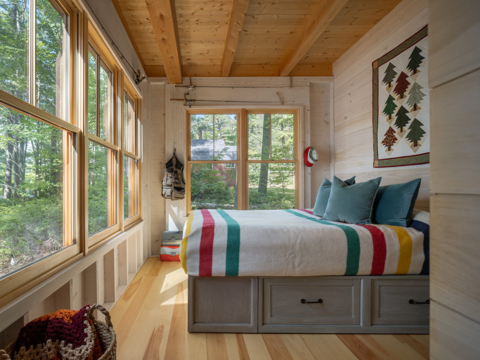 Uriges Schlafzimmer mit beiger Wandfarbe, hellem Holzboden, beigem Boden, freigelegten Dachbalken, Holzdecke und Holzwänden in Portland Maine