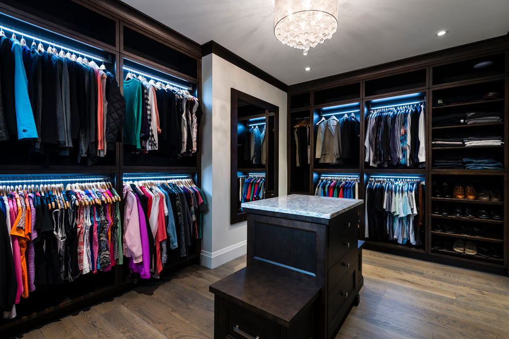 This is an example of a large traditional gender-neutral dressing room in Vancouver with recessed-panel cabinets, dark wood cabinets, medium hardwood floors and brown floor.