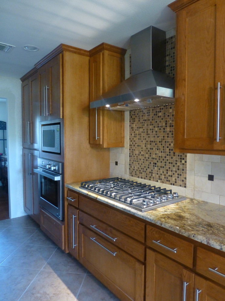 Kitchen pantry - large transitional galley ceramic tile kitchen pantry idea in Austin with an undermount sink, shaker cabinets, medium tone wood cabinets, granite countertops, multicolored backsplash, stone tile backsplash, stainless steel appliances and a peninsula