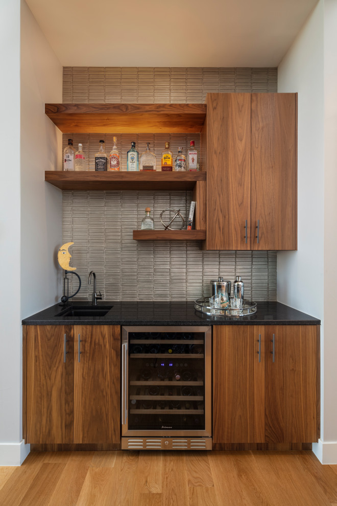 Wet bar - small contemporary light wood floor wet bar idea in Denver with an undermount sink, flat-panel cabinets, medium tone wood cabinets, quartz countertops, beige backsplash, glass tile backsplash and black countertops