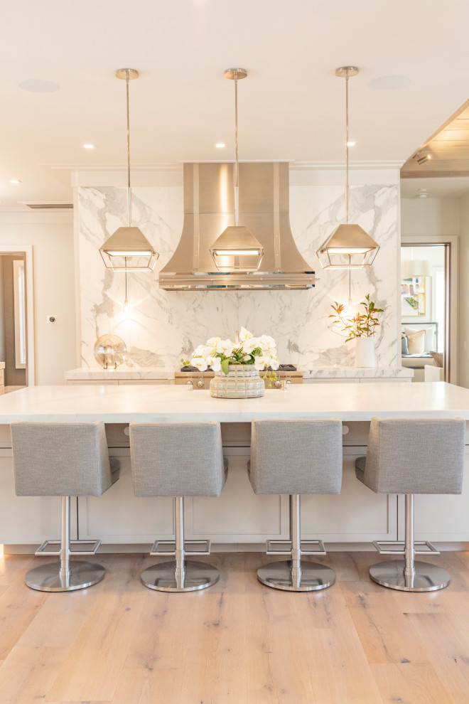 Inspiration for a large beach style l-shaped eat-in kitchen in Other with a farmhouse sink, shaker cabinets, grey cabinets, marble benchtops, white splashback, stone slab splashback, stainless steel appliances, light hardwood floors, with island, brown floor and white benchtop.