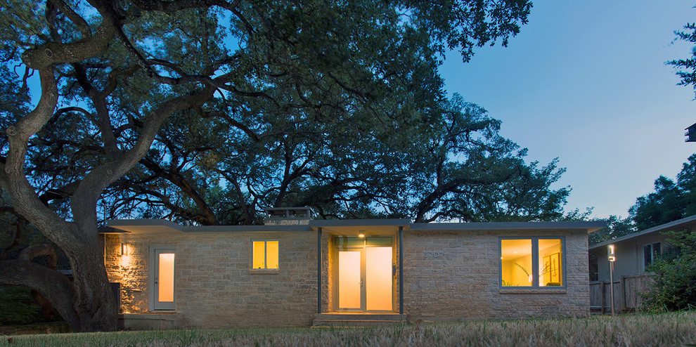 Photo of a midcentury one-storey exterior in Austin with stone veneer.