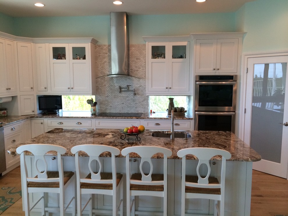 This is an example of a mid-sized transitional u-shaped open plan kitchen in Miami with shaker cabinets, white cabinets, granite benchtops, beige splashback, stainless steel appliances, medium hardwood floors and with island.