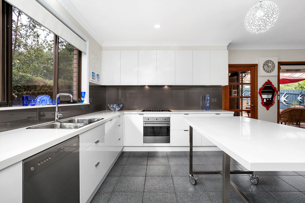 Design ideas for a large u-shaped kitchen pantry in Melbourne with a double-bowl sink, flat-panel cabinets, white cabinets, quartz benchtops, brown splashback, glass sheet splashback, stainless steel appliances, ceramic floors, with island and white benchtop.