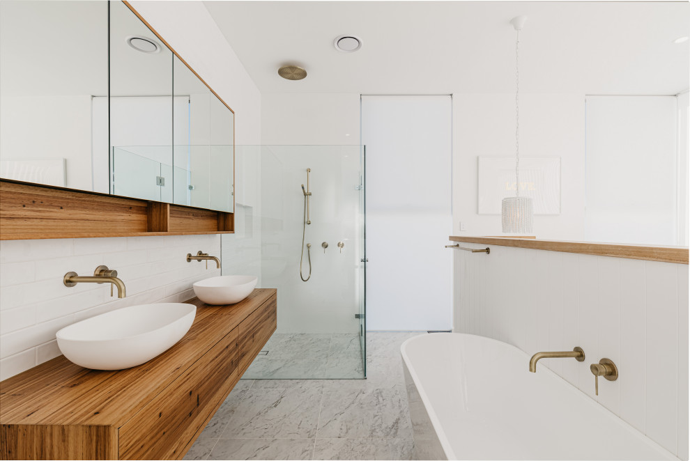 Inspiration for a contemporary bathroom in Sydney with flat-panel cabinets, medium wood cabinets, a freestanding tub, white tile, subway tile, white walls, an undermount sink, wood benchtops, grey floor, brown benchtops, a double vanity and a floating vanity.