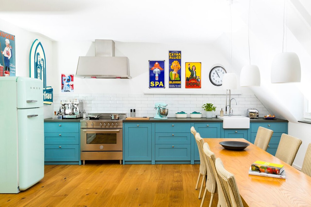 Mid-sized contemporary single-wall open plan kitchen in Cologne with a single-bowl sink, blue cabinets, white splashback, subway tile splashback, stainless steel appliances, medium hardwood floors, no island and beaded inset cabinets.