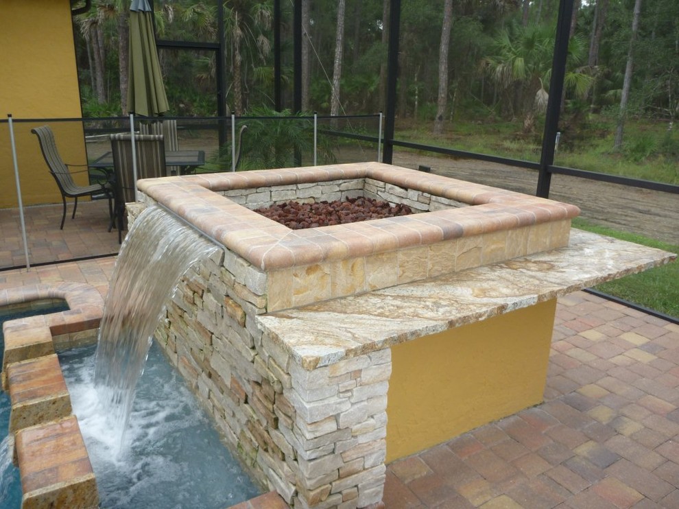 This is an example of a mid-sized mediterranean indoor round natural pool in Tampa with a water feature and brick pavers.