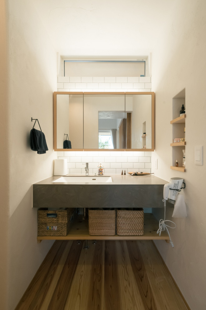 На фото: туалет в стиле модернизм с стеклянными фасадами, серыми фасадами, белыми стенами, паркетным полом среднего тона и встроенной тумбой с