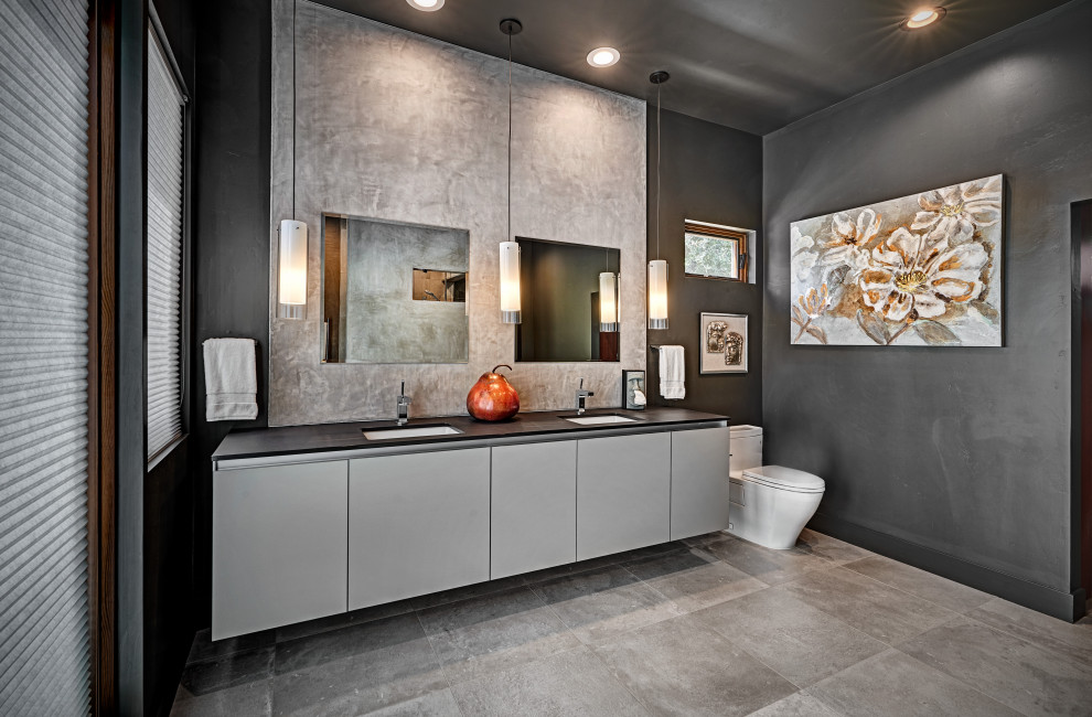 Huge trendy master gray tile cement tile floor, multicolored floor and double-sink bathroom photo in Sacramento with flat-panel cabinets, gray cabinets, a one-piece toilet, black walls, an undermount sink, quartz countertops, black countertops and a floating vanity