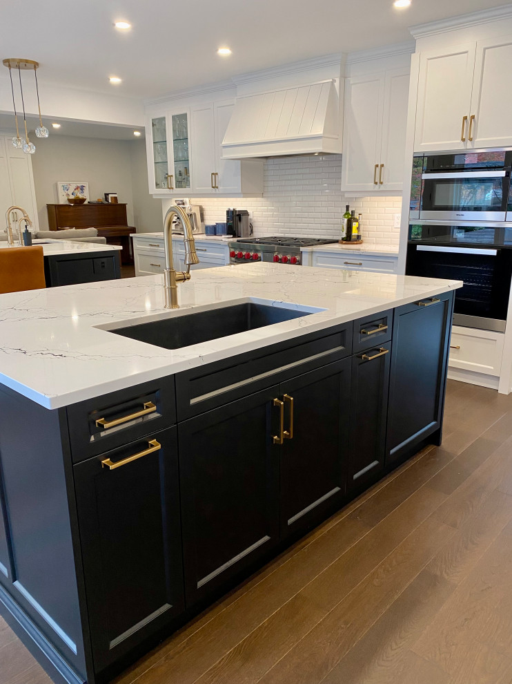 Inspiration for a large transitional medium tone wood floor kitchen remodel in Toronto with an undermount sink, recessed-panel cabinets, white cabinets, quartz countertops, white backsplash, porcelain backsplash, paneled appliances, two islands and white countertops