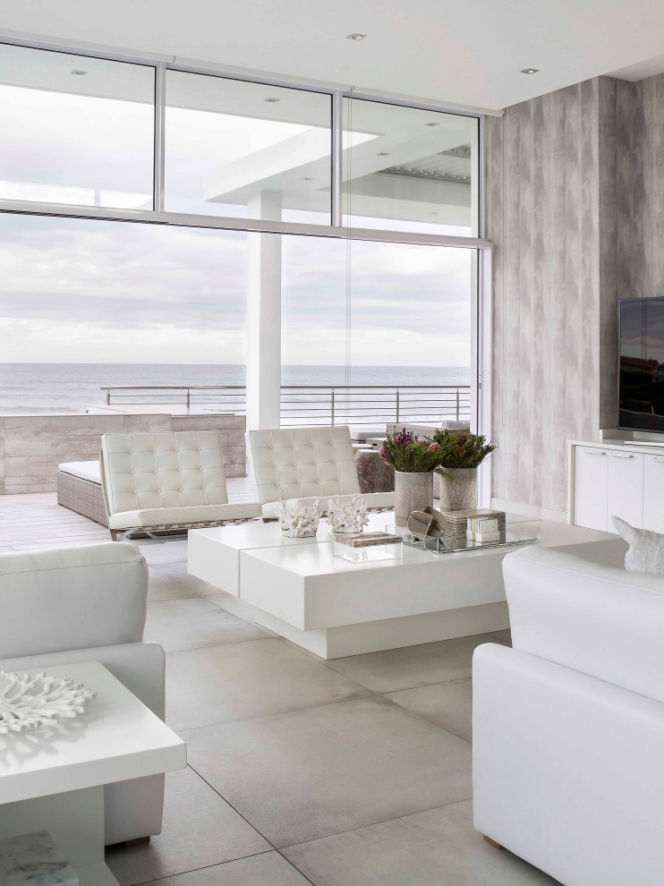 Inspiration for a large beach style open concept living room in Other with grey walls, a freestanding tv, grey floor and wallpaper.