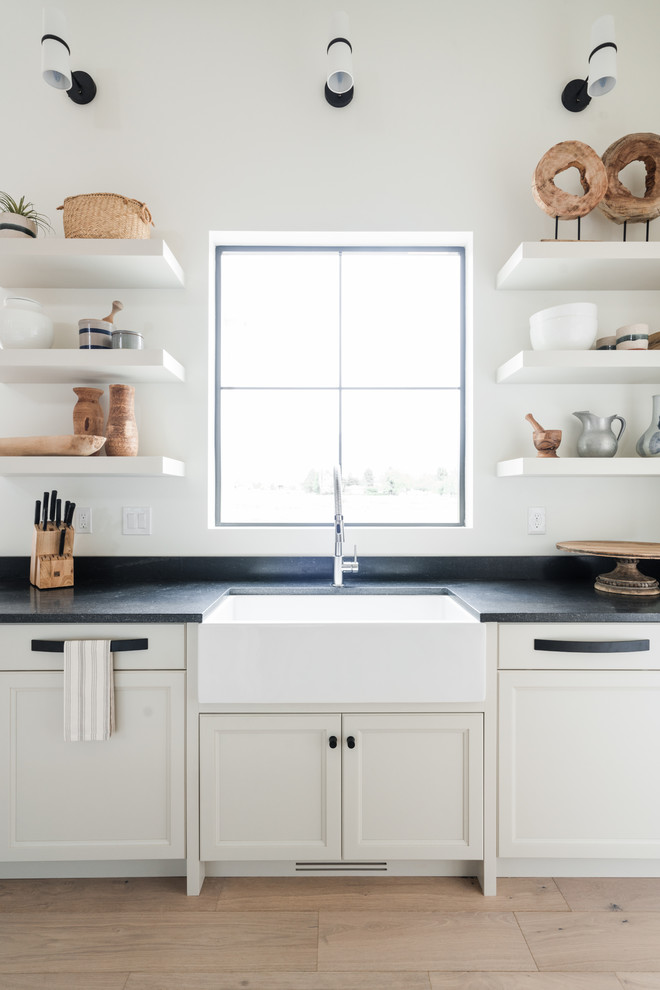 This is an example of a beach style eat-in kitchen in Other with a farmhouse sink and white cabinets.