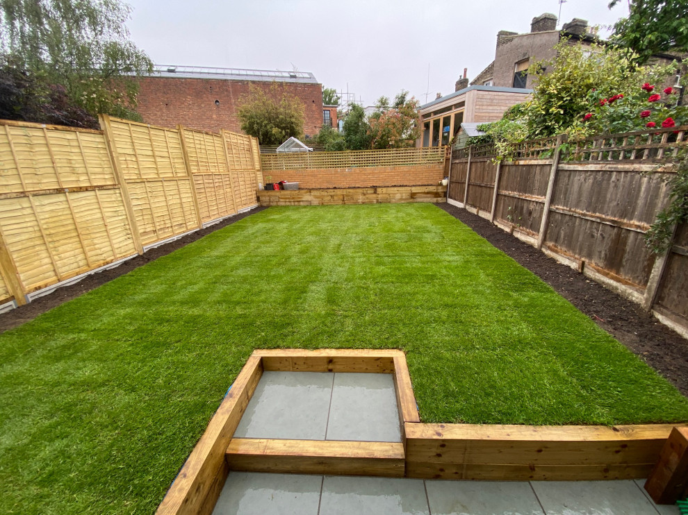 Design ideas for a mid-sized contemporary backyard full sun formal garden for summer in London with with lawn edging, brick pavers and a wood fence.