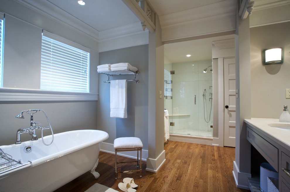 This is an example of a large arts and crafts master bathroom in New York with shaker cabinets, grey cabinets, a claw-foot tub, an alcove shower, grey walls, medium hardwood floors, an undermount sink and engineered quartz benchtops.