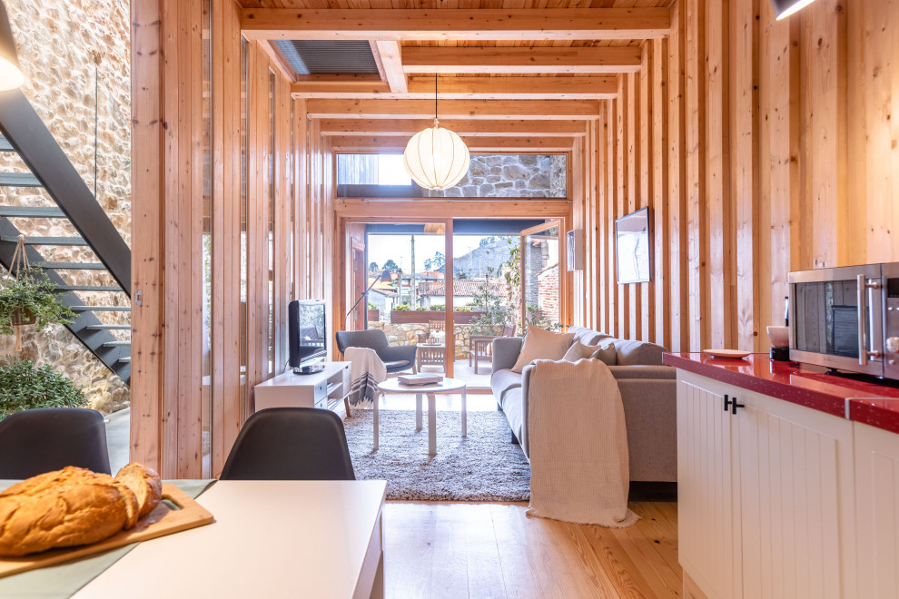 Idee per un soggiorno nordico aperto con parquet chiaro, TV autoportante, soffitto in legno e pareti in legno