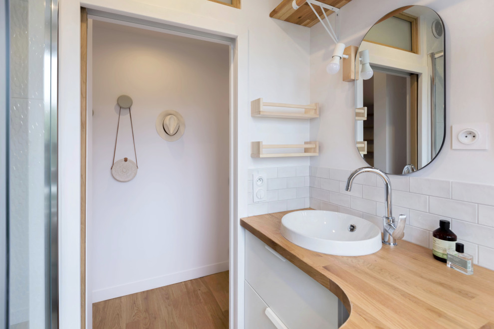 На фото: маленькая ванная комната в белых тонах с отделкой деревом в скандинавском стиле с белой плиткой и душевой кабиной для на участке и в саду с
