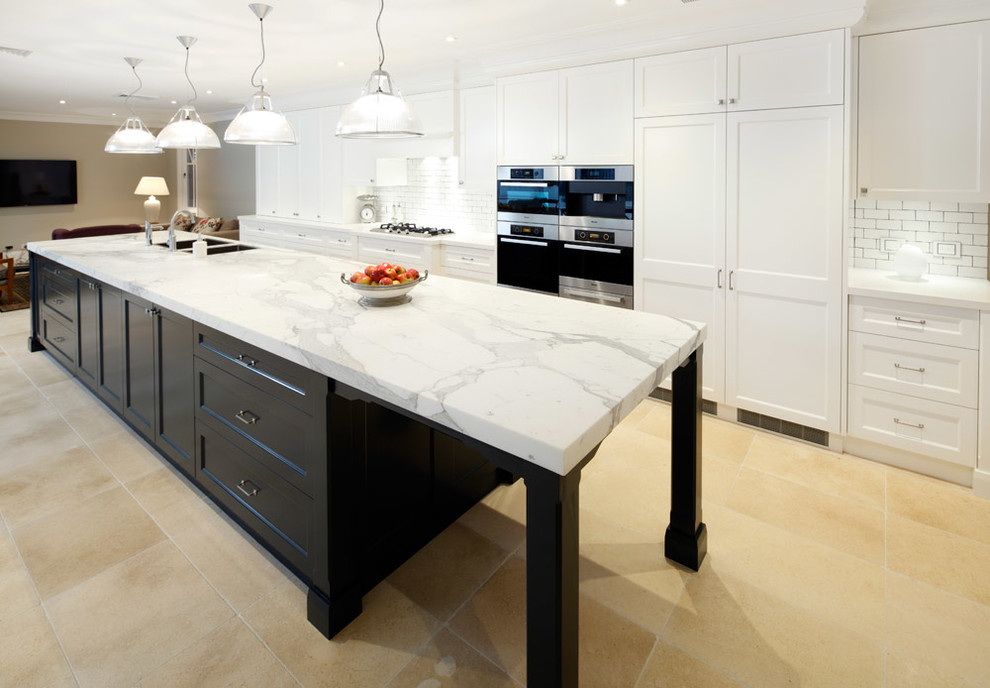 This is an example of an expansive traditional galley eat-in kitchen in Sydney with a drop-in sink, shaker cabinets, white cabinets, marble benchtops, white splashback, brick splashback, stainless steel appliances, ceramic floors, with island and beige floor.