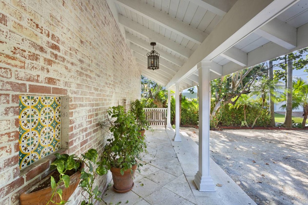 Inspiration for a mid-sized tropical front yard verandah in Miami with concrete pavers and a roof extension.