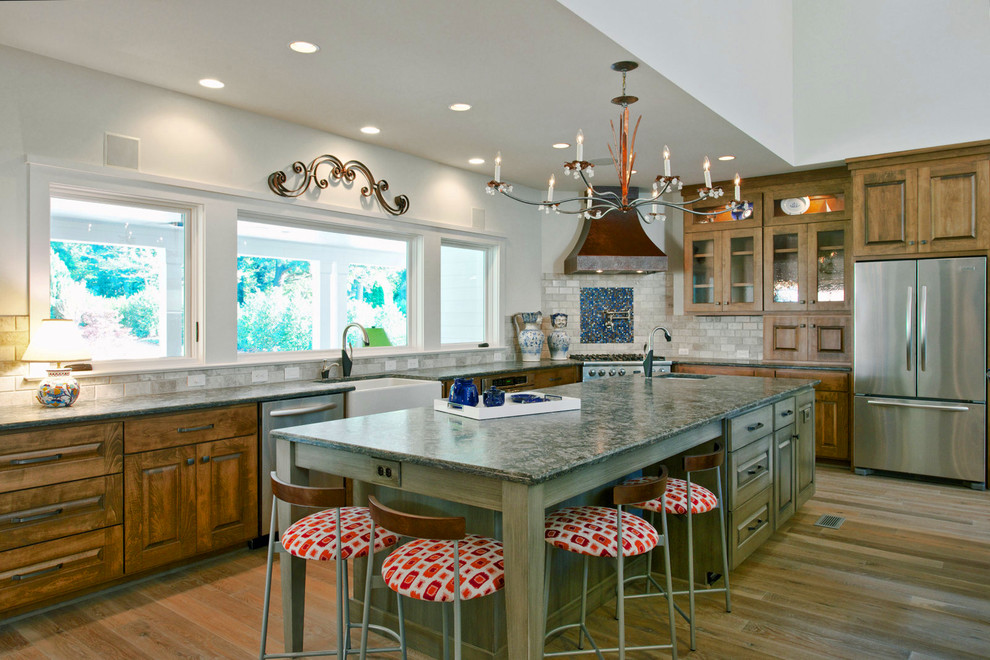 Design ideas for a large contemporary l-shaped open plan kitchen in Raleigh with a farmhouse sink, raised-panel cabinets, medium wood cabinets, beige splashback, ceramic splashback, stainless steel appliances, granite benchtops, medium hardwood floors and with island.