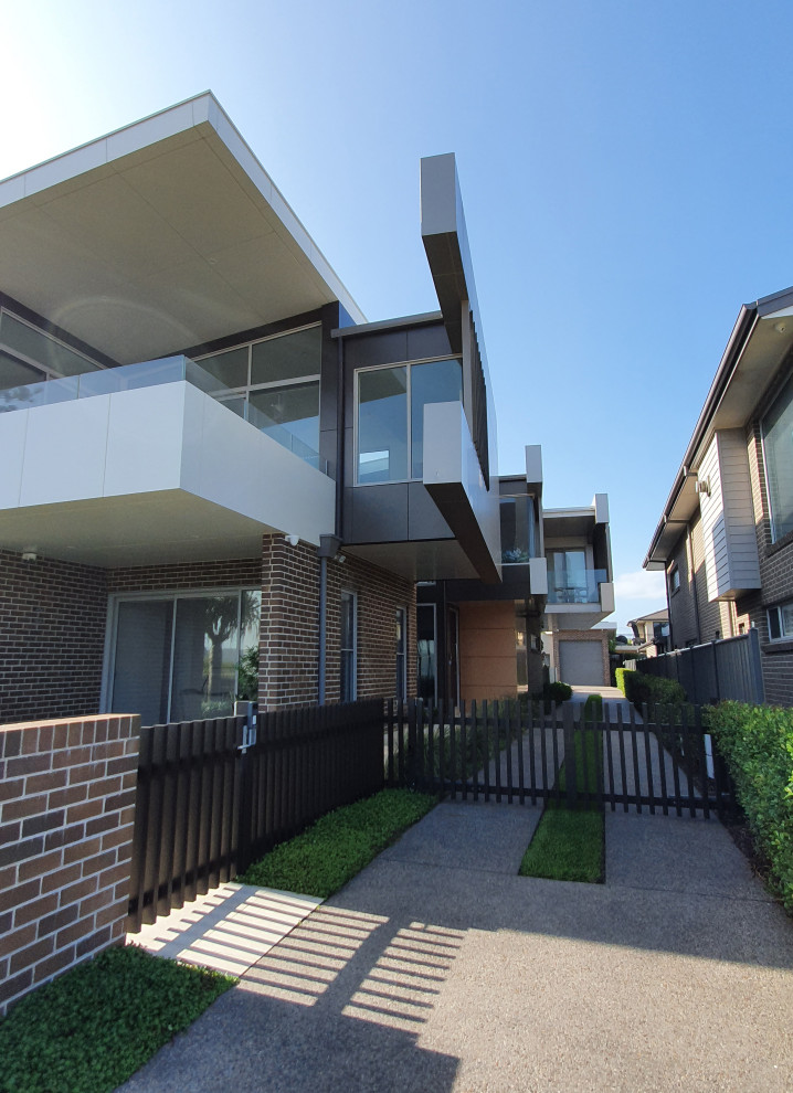 Large contemporary two-storey house exterior in Central Coast with metal siding, a flat roof and a metal roof.