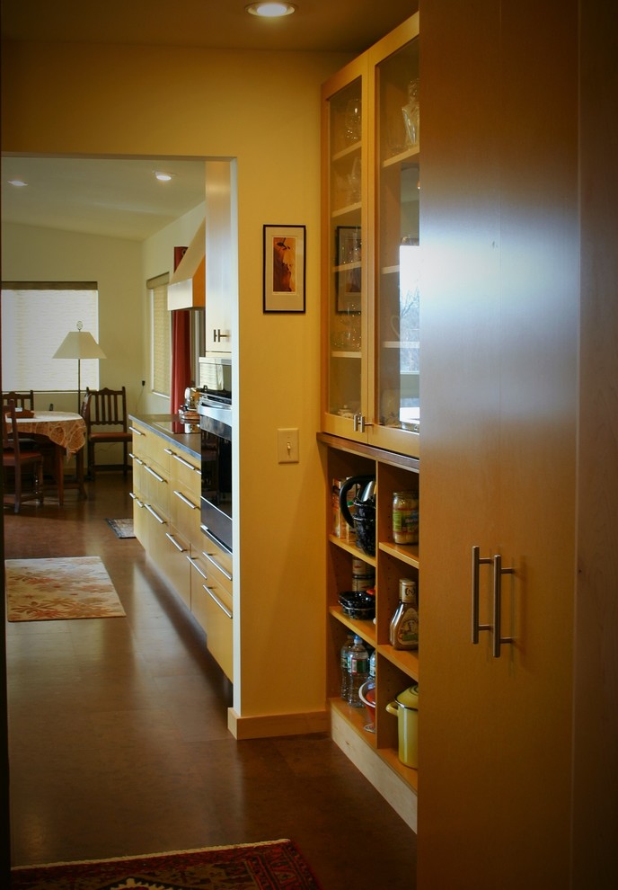 Mid-sized contemporary galley kitchen pantry in Burlington with an undermount sink, flat-panel cabinets, yellow cabinets, solid surface benchtops, stainless steel appliances, cork floors, with island and brown floor.
