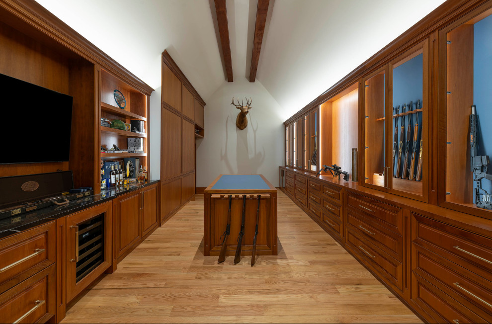 This is an example of an expansive traditional gender neutral walk-in wardrobe in Dallas with raised-panel cabinets, dark wood cabinets, light hardwood flooring, brown floors and a vaulted ceiling.