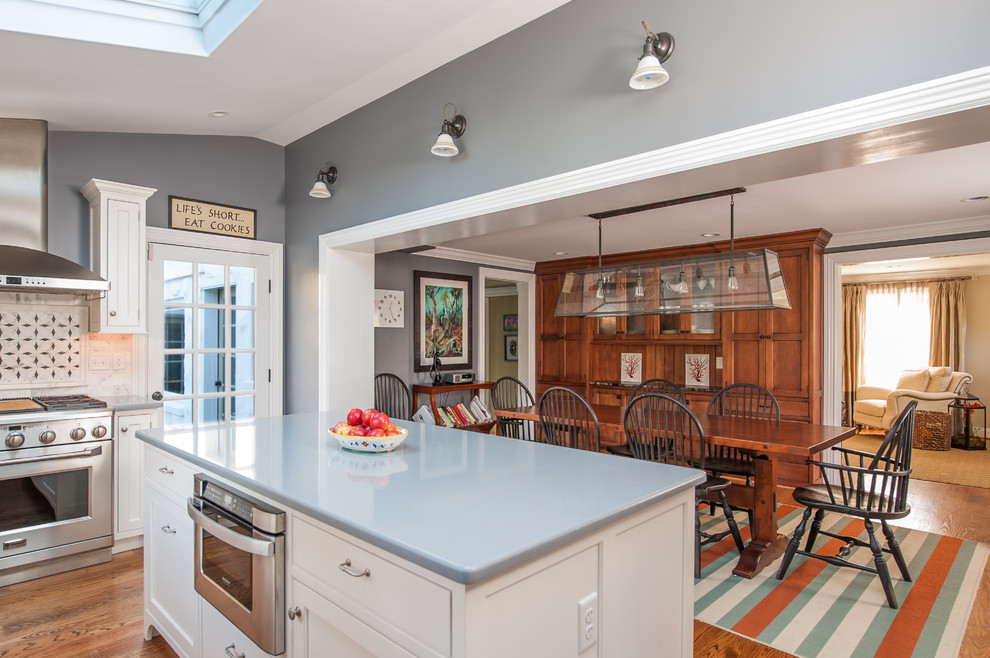Photo of a traditional u-shaped eat-in kitchen in Philadelphia with recessed-panel cabinets, white cabinets, multi-coloured splashback, stainless steel appliances, a farmhouse sink, granite benchtops and stone tile splashback.