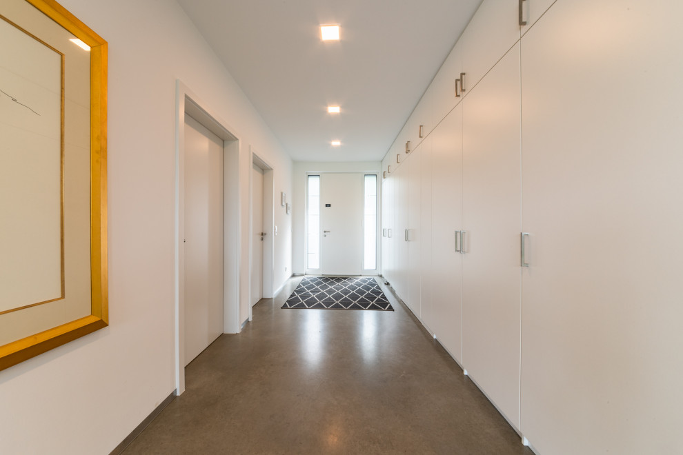 Inspiration for a modern hallway in Essen with white walls, concrete floors and grey floor.