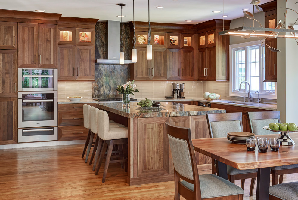 Eat-in kitchen - traditional l-shaped medium tone wood floor and orange floor eat-in kitchen idea in Chicago with an undermount sink, medium tone wood cabinets, beige backsplash, glass tile backsplash, stainless steel appliances and an island