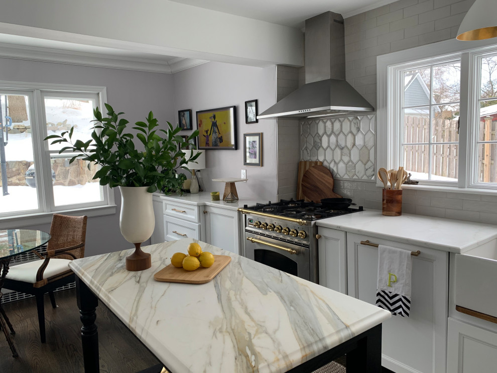 Klassisk inredning av ett mellanstort vit vitt kök och matrum, med en rustik diskho, luckor med infälld panel, vita skåp, marmorbänkskiva, grått stänkskydd, stänkskydd i keramik, integrerade vitvaror, mellanmörkt trägolv, en köksö och brunt golv