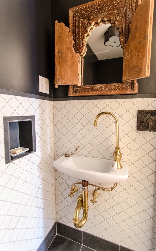 This is an example of a mediterranean powder room in New York with a wall-mount sink and black tile.