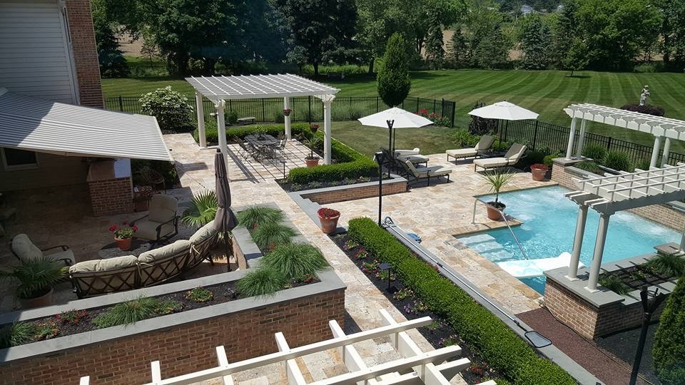 This is an example of a traditional backyard l-shaped natural pool in Philadelphia with a water feature and natural stone pavers.