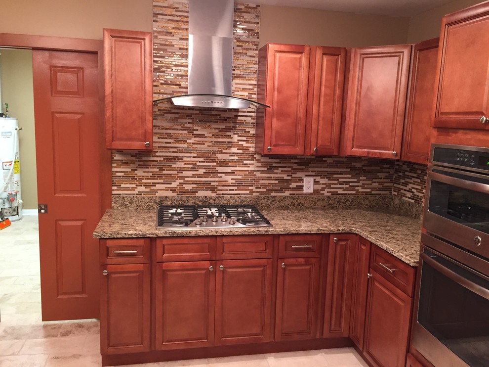 Photo of a mid-sized traditional u-shaped eat-in kitchen in Atlanta with a farmhouse sink, recessed-panel cabinets, medium wood cabinets, granite benchtops, multi-coloured splashback, mosaic tile splashback, stainless steel appliances, travertine floors and no island.