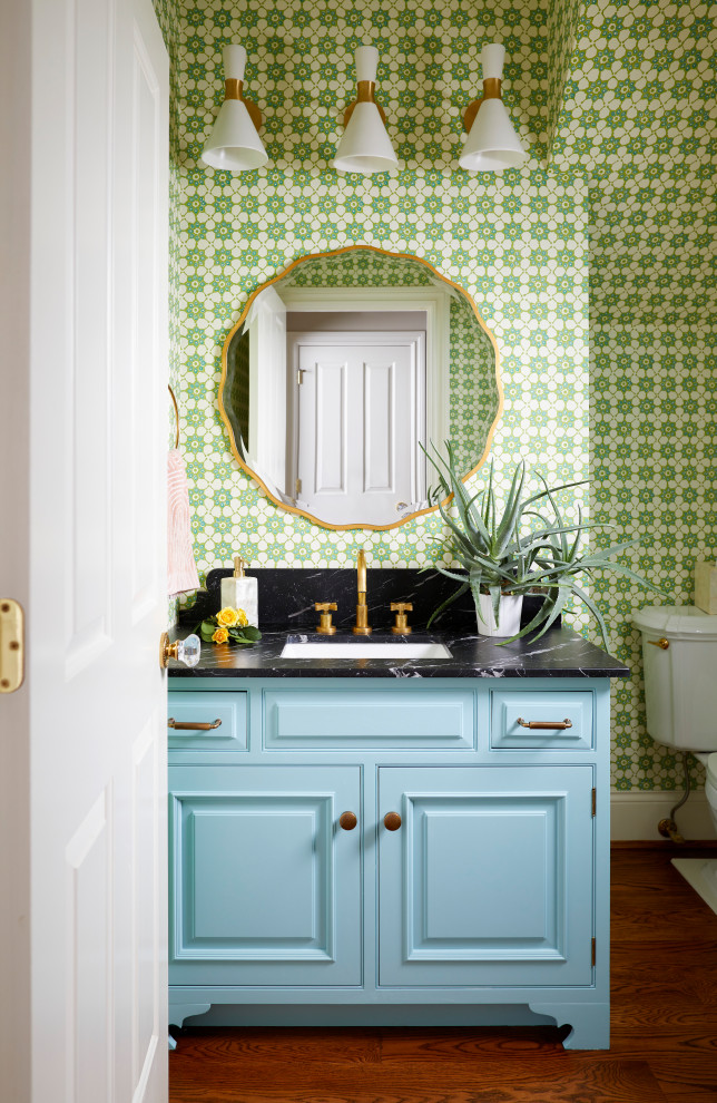 Ispirazione per un bagno di servizio chic con ante blu, pareti verdi, pavimento in legno massello medio, pavimento marrone, top nero e carta da parati
